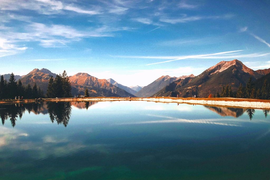 Peaceful mountain lake reflecting the surrounding landscape under a stunning sunset sky.